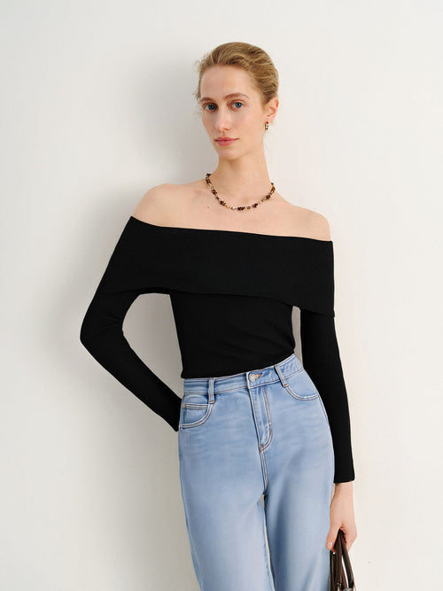 Load image 1 in gallery view. Woman wearing a black off-shoulder top and light blue jeans against a white background