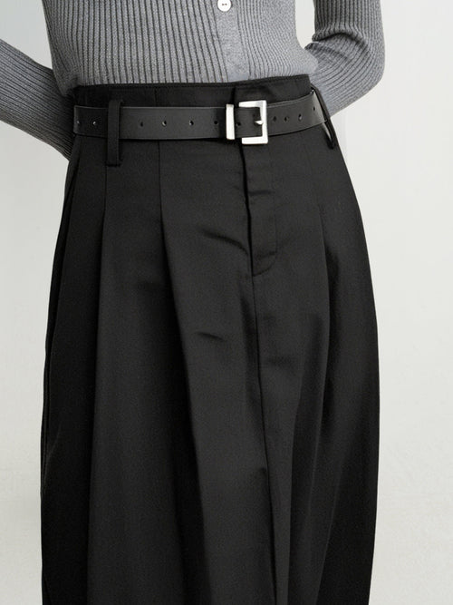 Charger l'image 1 dans la galerie. Person wearing a gray sweater and black pleated pants with a belt on a light gray background