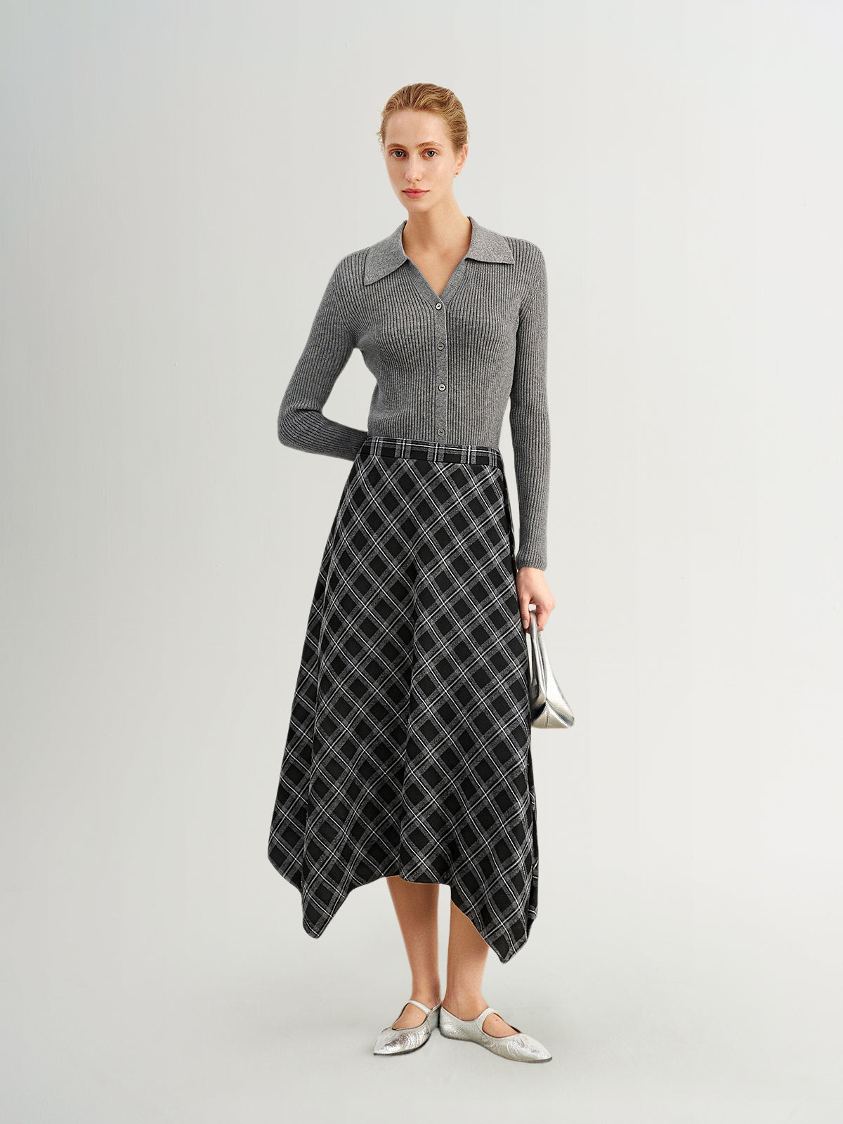 Woman wearing a gray sweater and plaid skirt on a white background