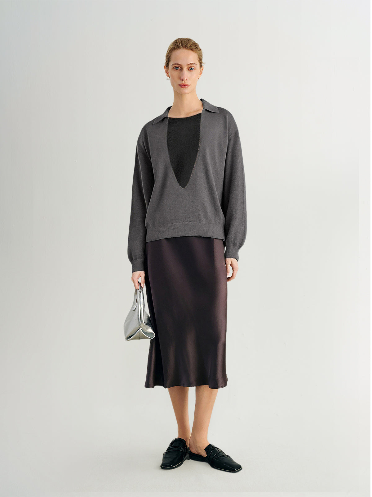 Woman wearing a gray sweater and black skirt on a white background