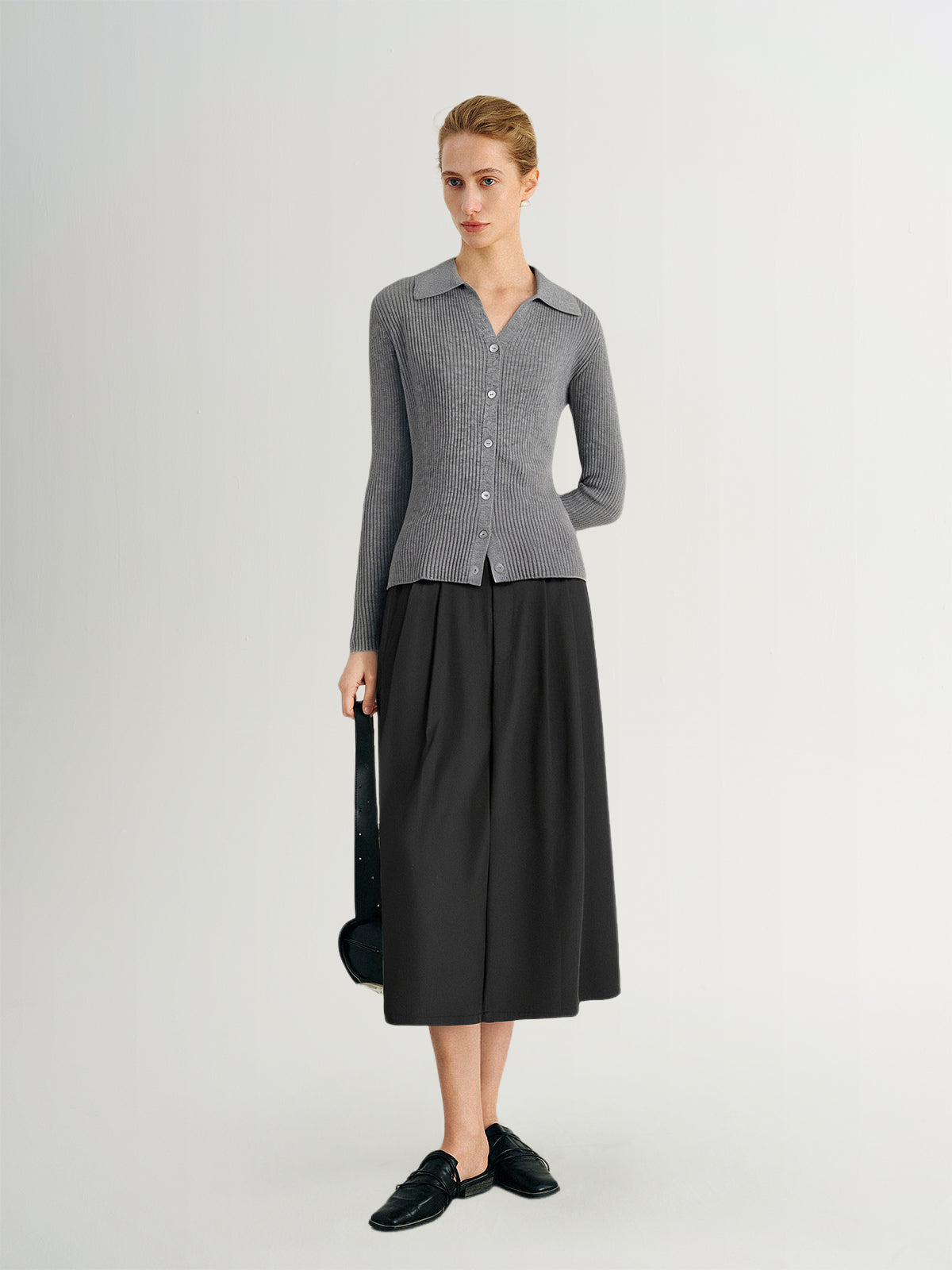 Woman wearing a gray checkered shirt and black skirt on a white background