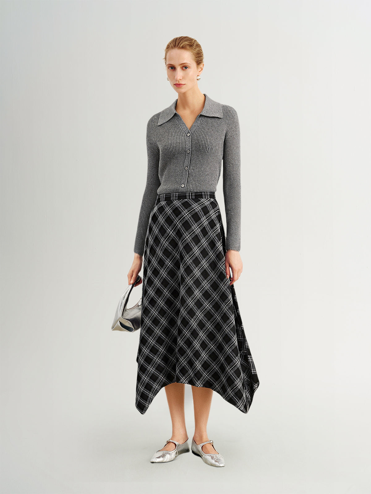 Woman wearing a gray sweater and black plaid skirt on a white background