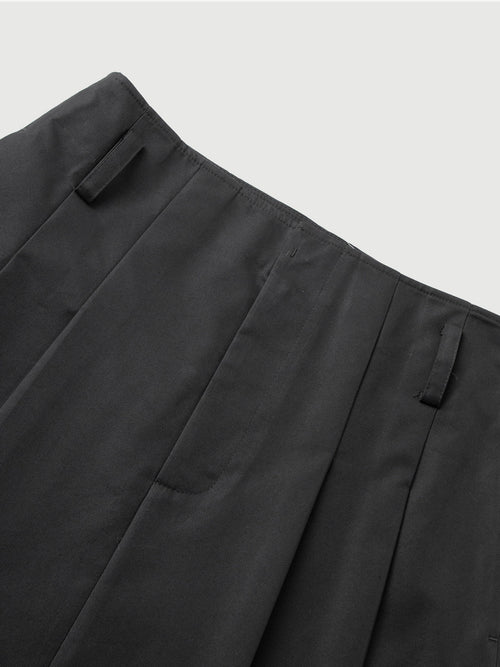Charger l'image 1 dans la galerie. Close-up of dark gray pants with pleats on a light gray background